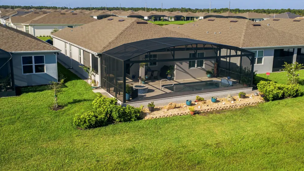 Aerial view of a completed backyard — pool, screen enclosure, and outdoor kitchen, Melbourne, Florida