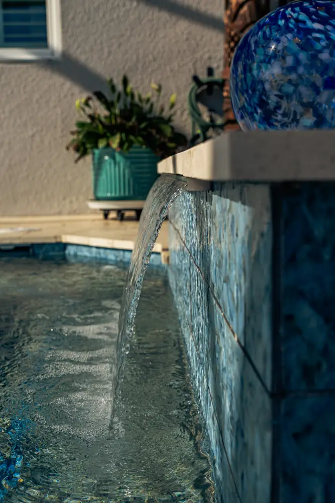 Sheer waterfall descending a tiled wall into the pool