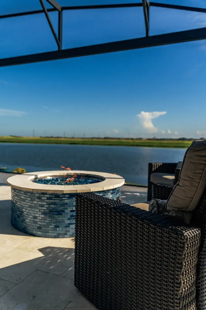 Round tiled fire pit with wicker seating by the lake