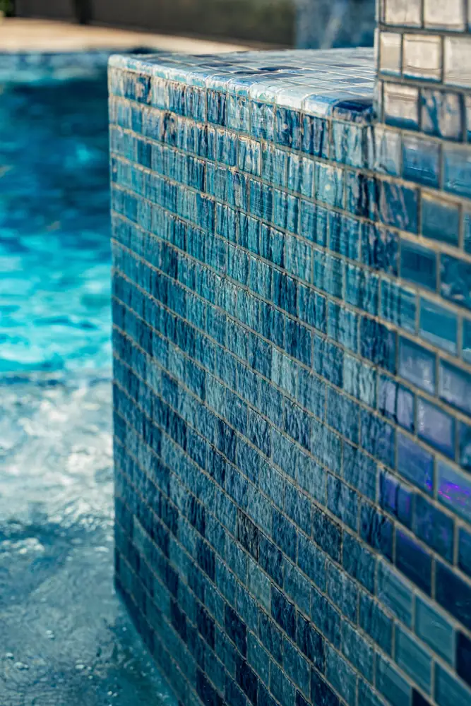 Blue glass tile spa wall beside pool water