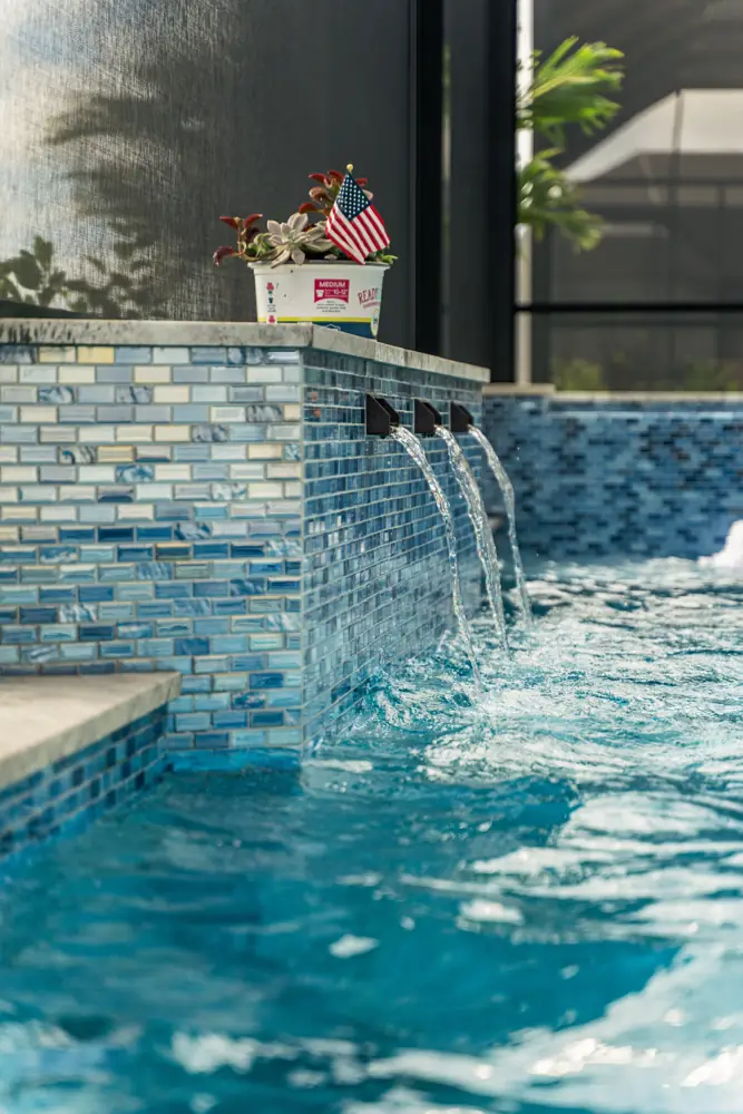 Waterfall scuppers over a glass tile wall into the pool