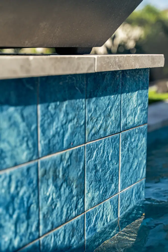 Textured blue tile pedestal beside the pool