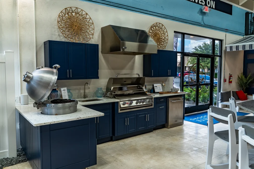 Navy outdoor kitchen display with grill, hood, and kamado