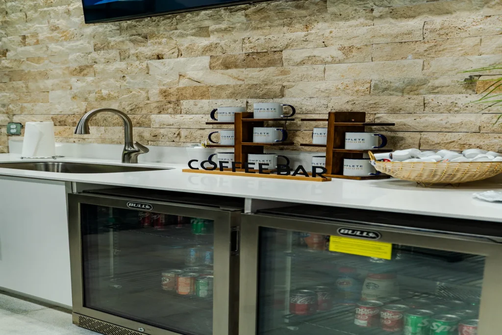 Coffee bar with travertine ledger wall and branded mugs
